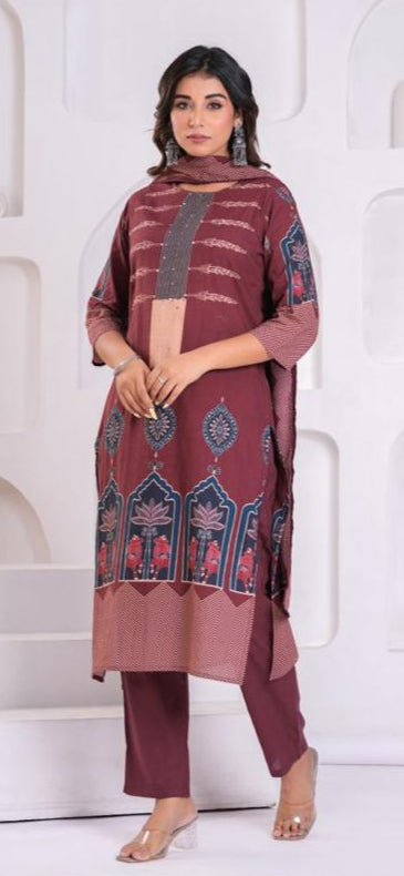 Woman wearing a maroon traditional outfit with intricate patterns in a white architectural setting